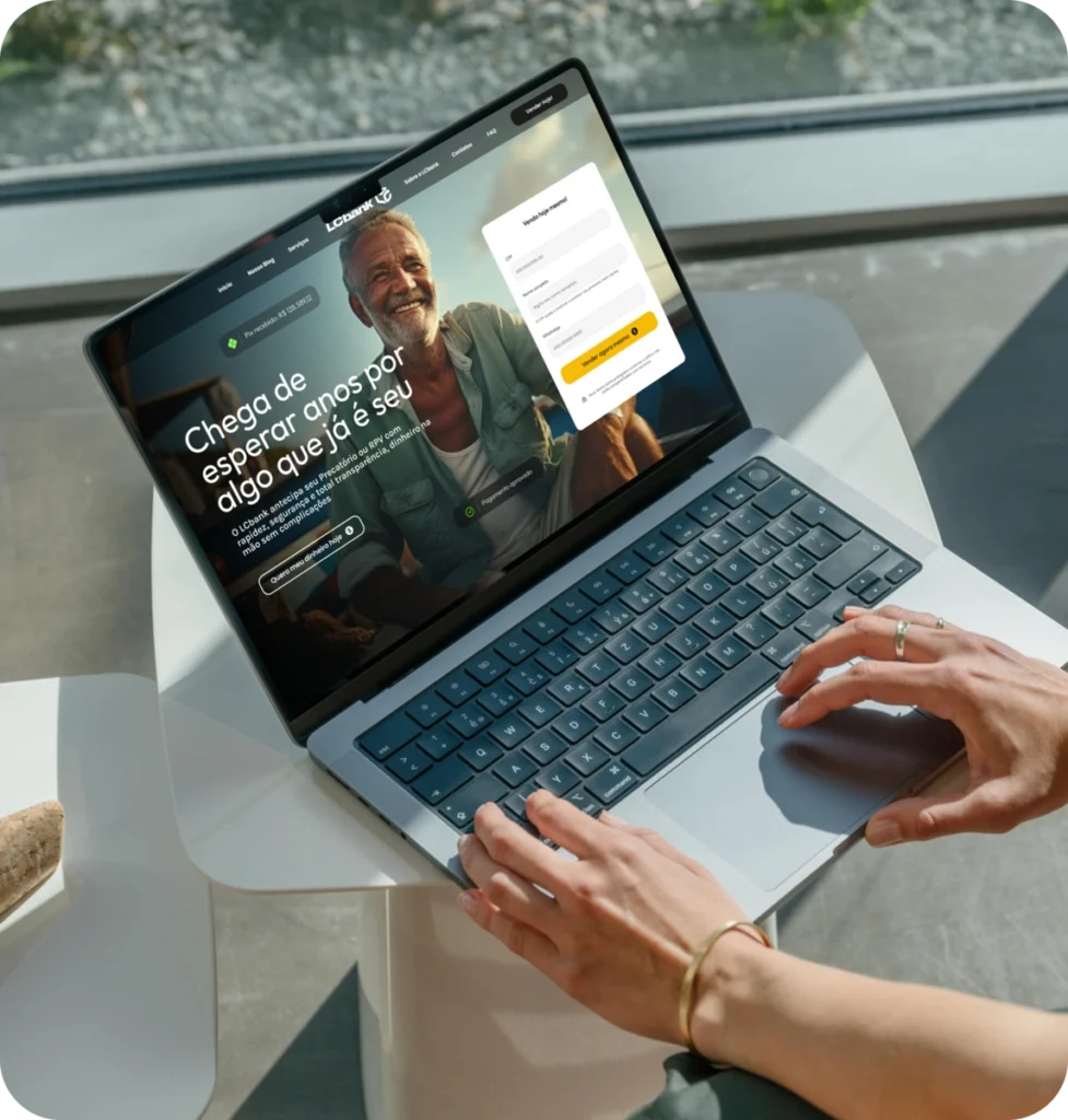 Laptop aberto mostrando site do LCbank com homem sorrindo e texto "Chega de esperar.